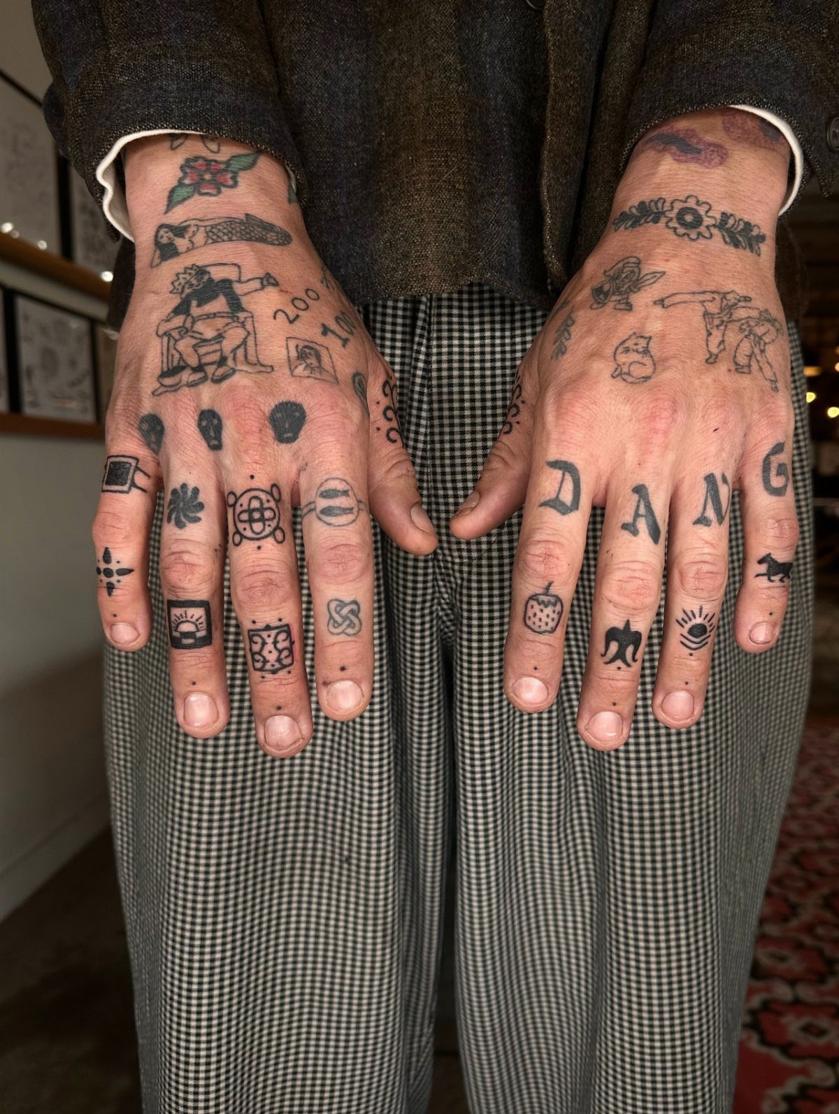 Tattooed hands with the word DANG across the knuckles and various finger symbols.
