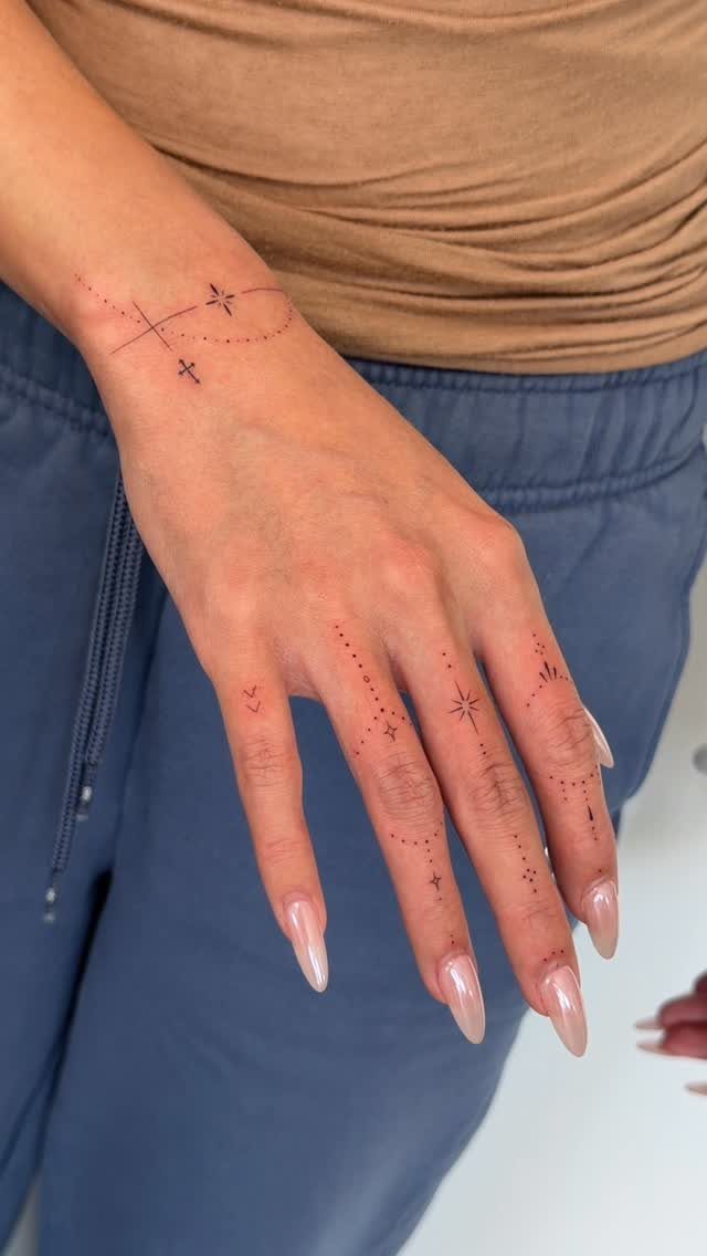 Hand and wrist with delicate red ink tattoos of dots and stars