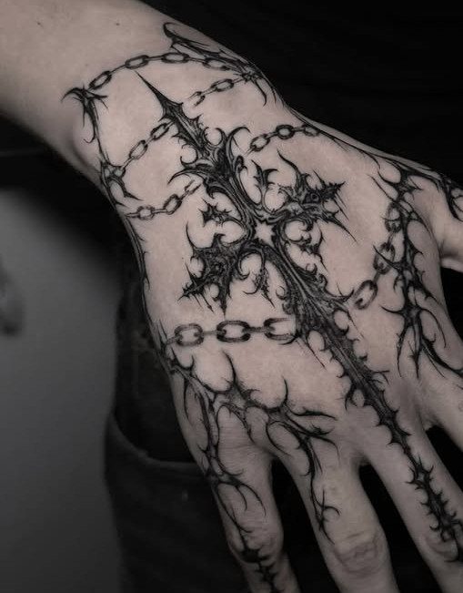 15 Hand Pen Tattoo Ideas for Spider Webs, Flowers and More 8 Gothic cross tattoo with chains and thorns on a person's hand