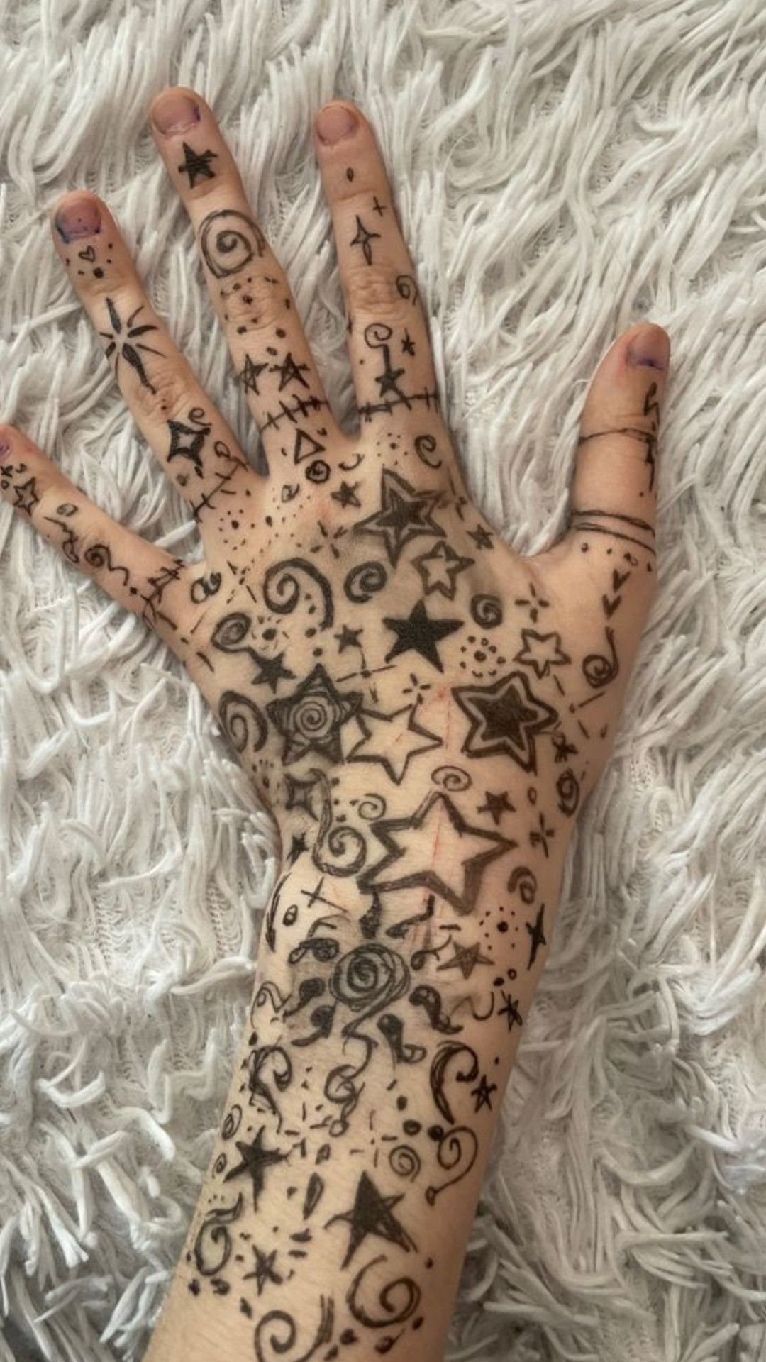 15 Hand Pen Tattoo Ideas for Spider Webs, Flowers and More 12 Hand and wrist covered in black ink doodle tattoos of stars and swirls.