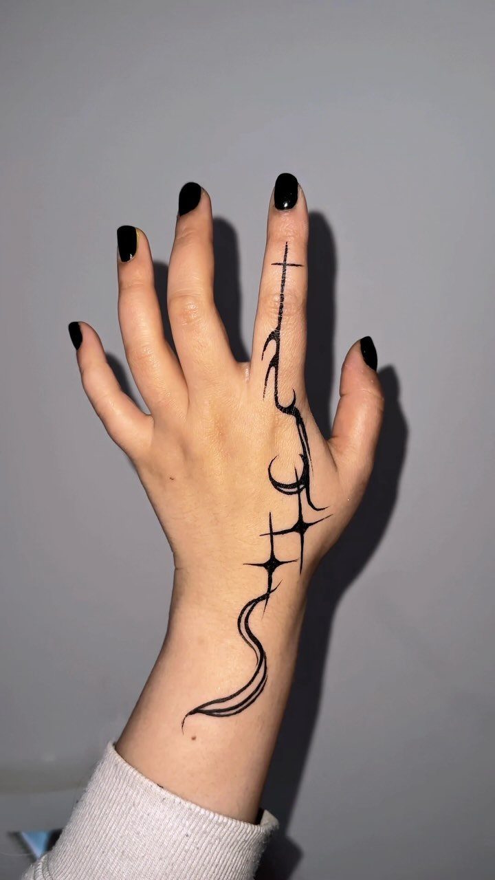 15 Hand Pen Tattoo Ideas for Spider Webs, Flowers and More 11 Hand with black nail polish and a swirling line tattoo with a cross.