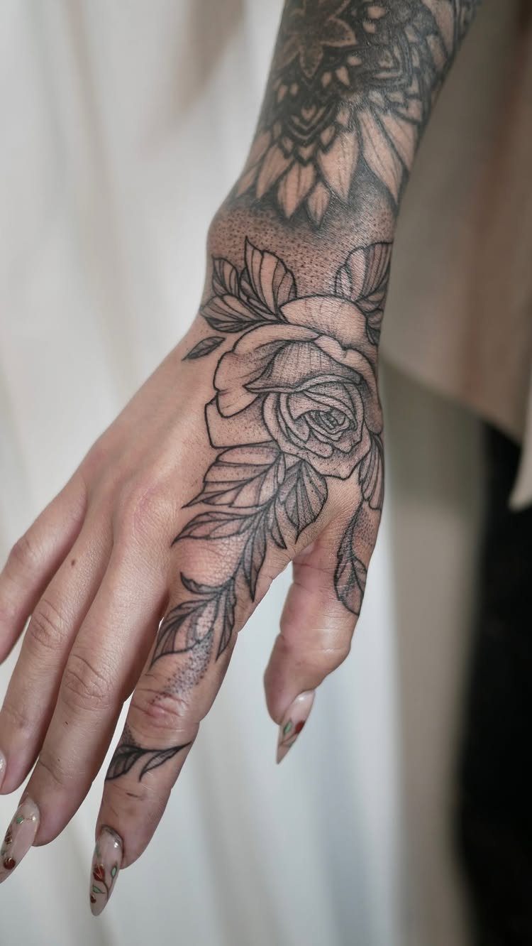 Rose tattoo with leaves on the back of a hand and wrist.