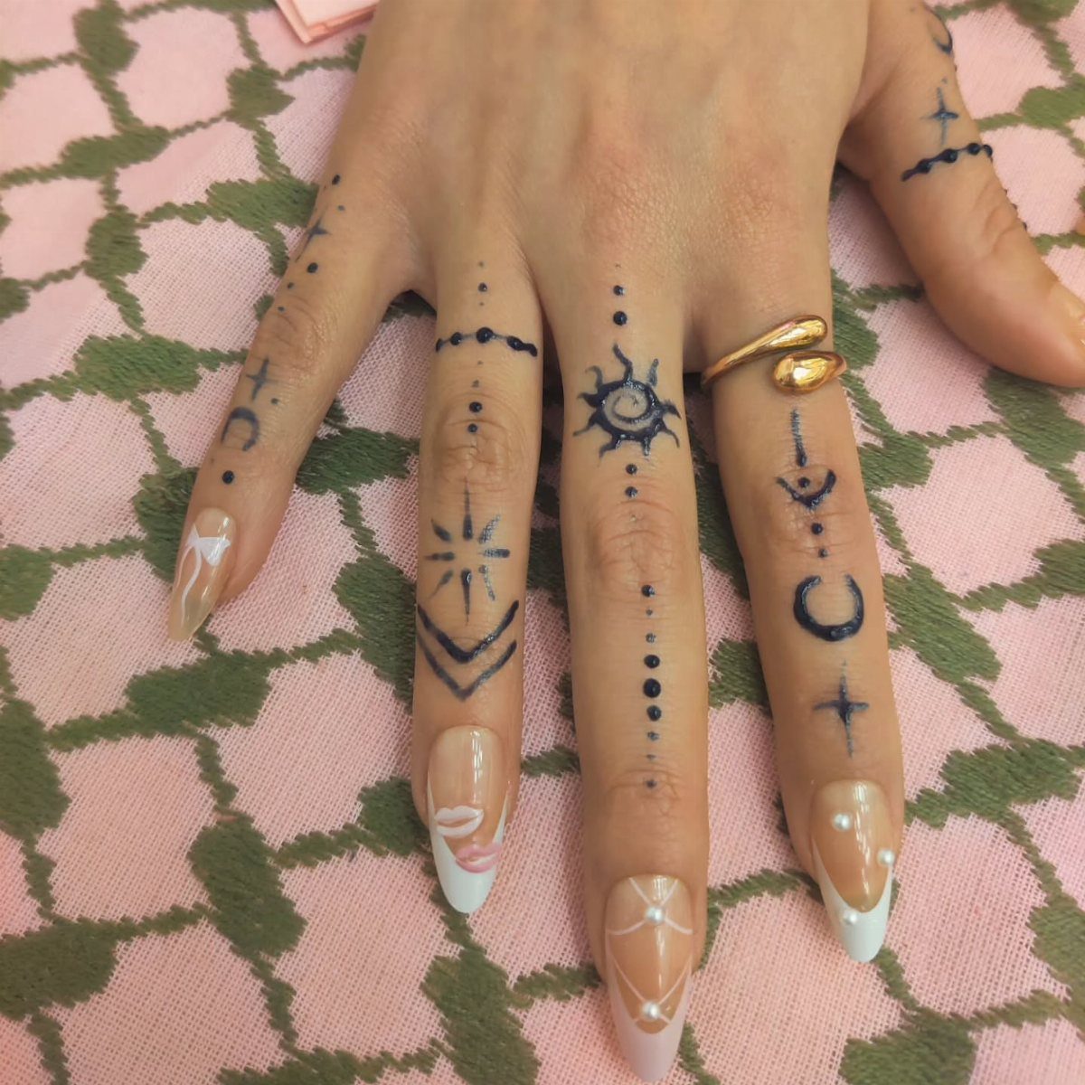 6 Hand Tattoo Henna Style Ideas for Every Taste 3 Hand with dark blue celestial henna tattoos on fingers and long manicured nails.