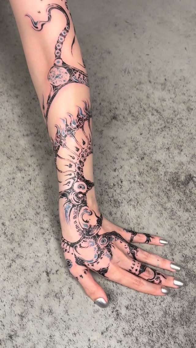 6 Hand Tattoo Henna Style Ideas for Every Taste 4 Arm and hand with intricate black and blue henna sleeve tattoo designs.