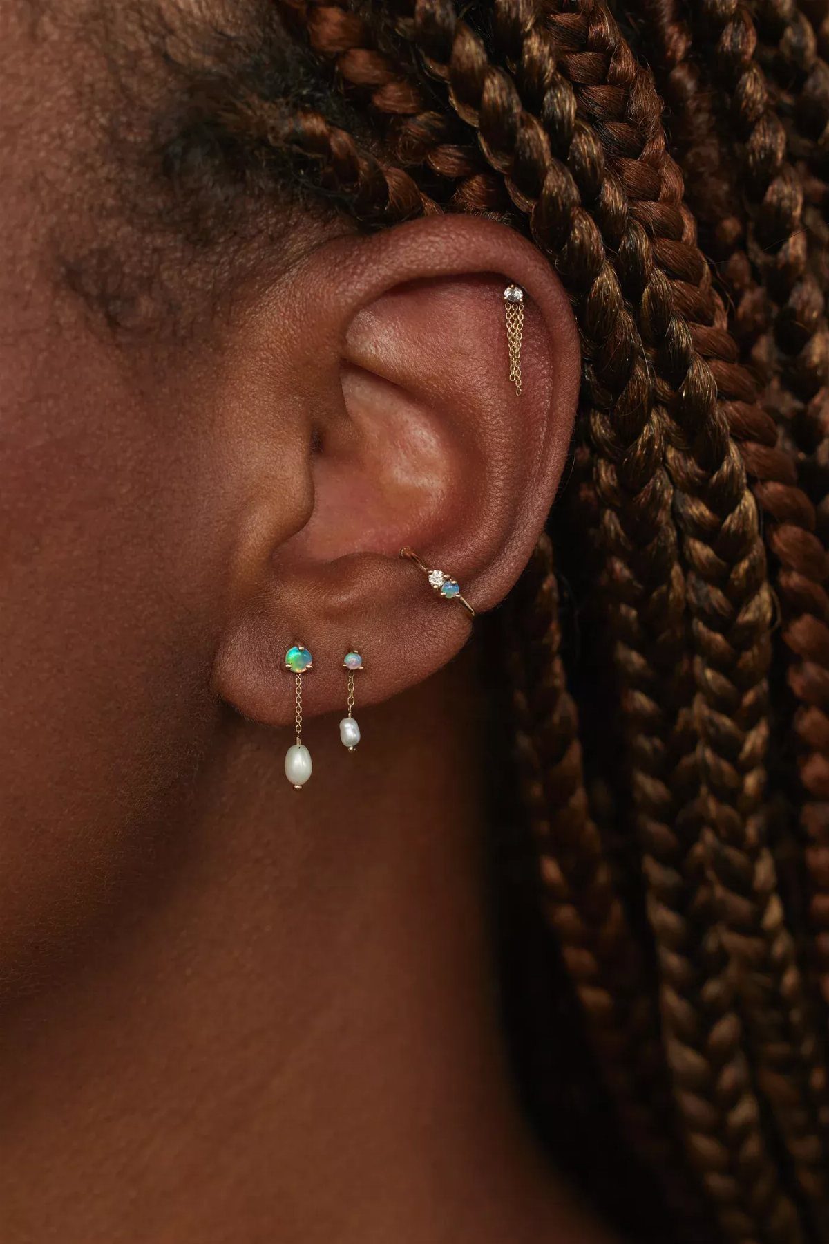 Hanging Ear Piercing Ideas: 6 Chain, Pearl and Star Styles 5 Ear with multiple piercings featuring a gold chain earring with a hanging pearl.