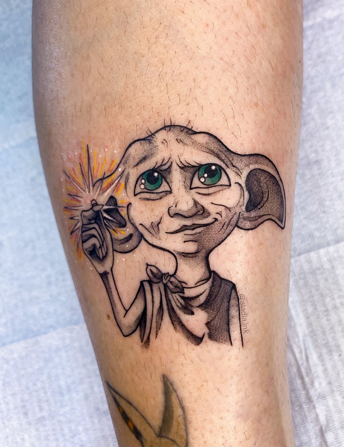 Dobby the House-Elf tattoo with green eyes and magical sparks on skin
