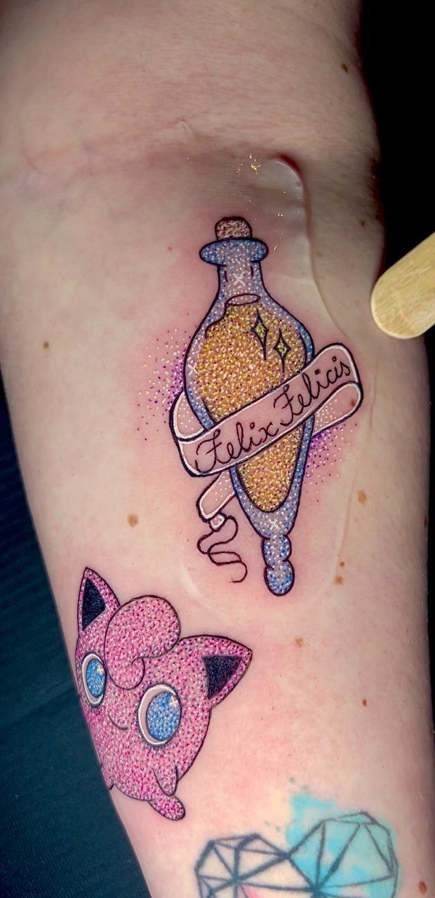 Felix Felicis potion bottle tattoo with golden liquid and purple sparkles on skin.