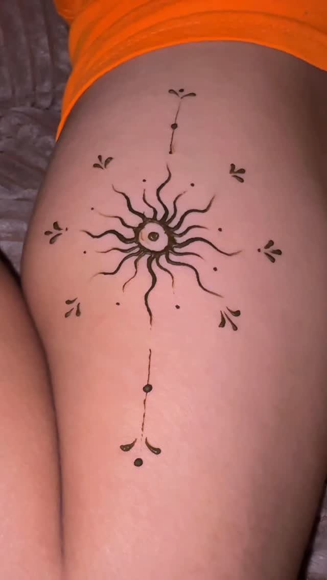 Henna sun tattoo with an eye in the center on a person's hip.