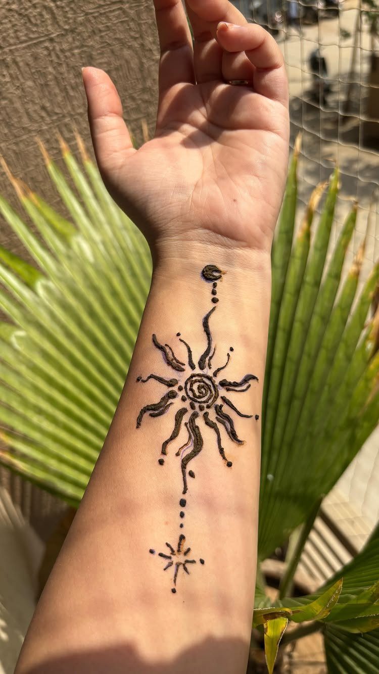 Henna sunburst tattoo with flame-like rays and a spiral center on a forearm