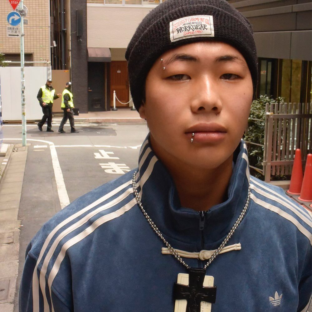 Person with a black beanie and blue jacket featuring eyebrow and lip piercings.