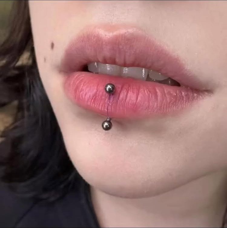 Labret lip piercing with silver barbell jewelry on a person's lower lip.