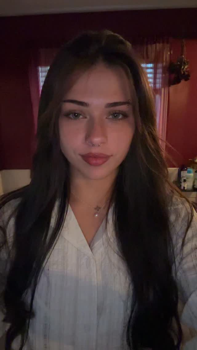 Young woman with long dark hair and a small eyebrow piercing stud.