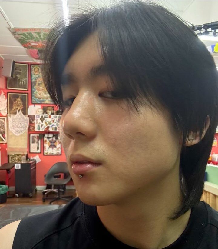 Person with dark hair wearing a silver labret stud lip piercing.