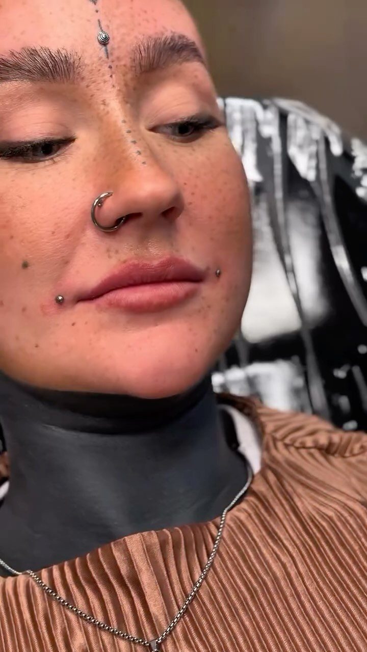 Lip Piercings for Small Lips: 7 Styles to Consider 6 Person with freckles showing dahlia piercings at the corners of their mouth.