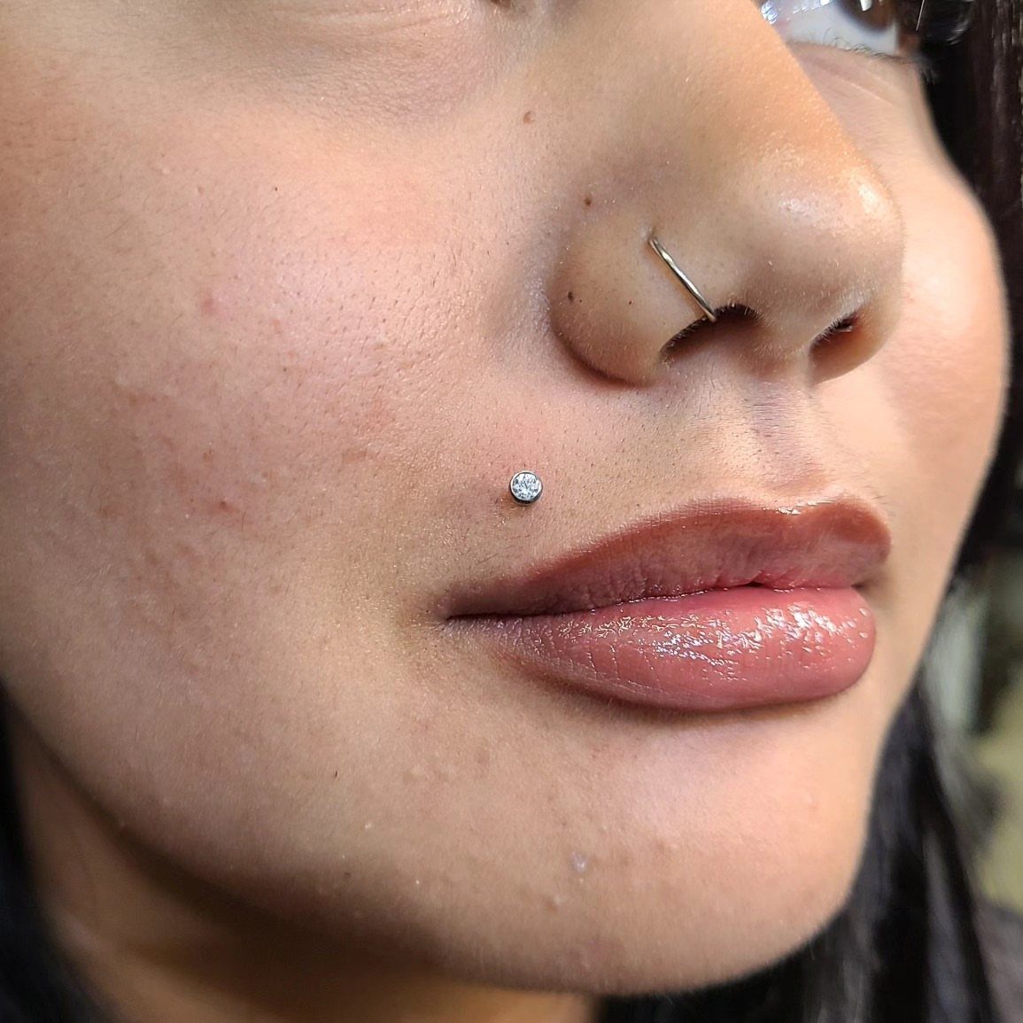 Lip Piercings for Small Lips: 7 Styles to Consider 1 Person with a sparkling Monroe piercing on the upper lip and a nose hoop.