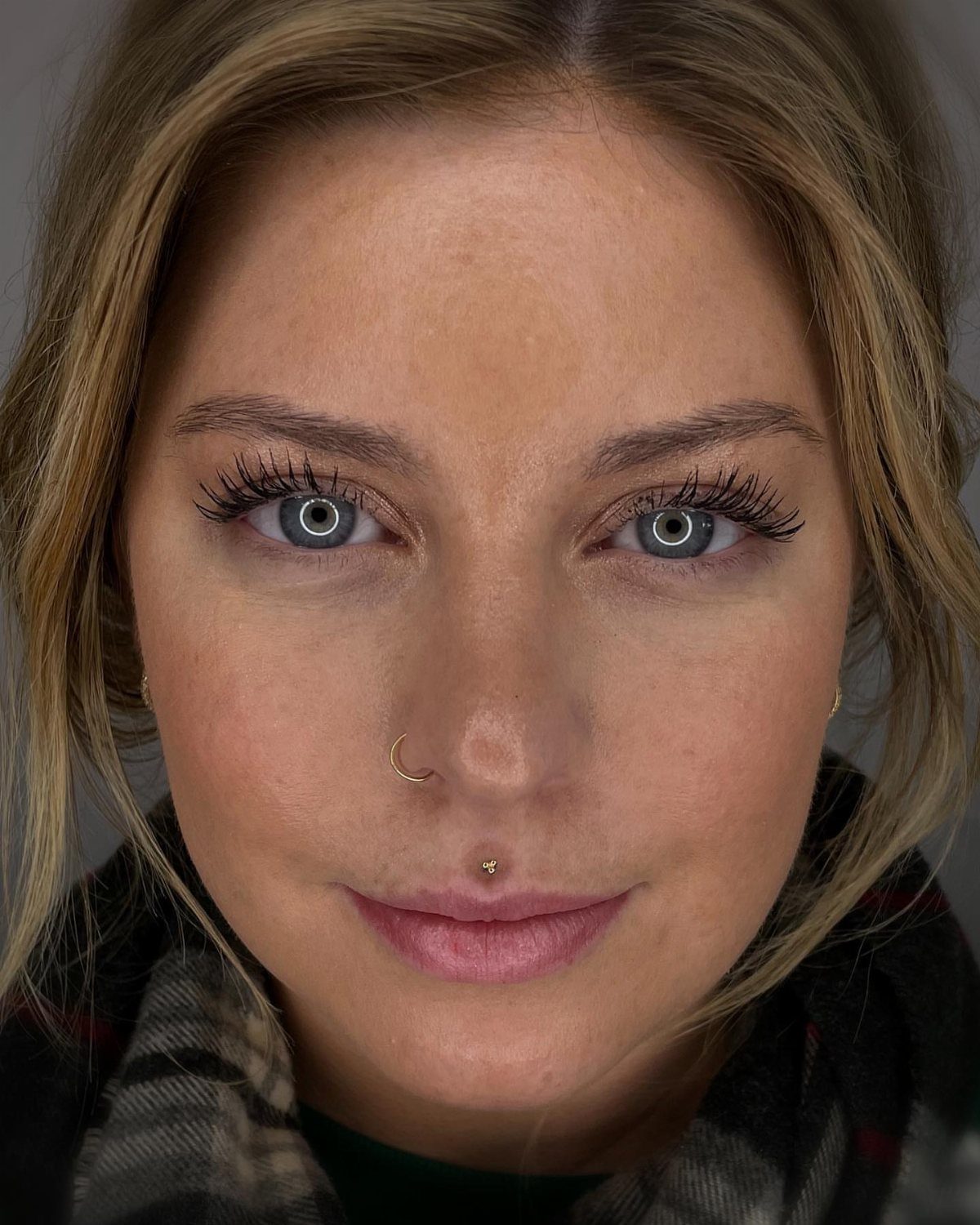 Lip Piercings for Small Lips: 7 Styles to Consider 5 Woman with a gold philtrum piercing and a gold nose ring.
