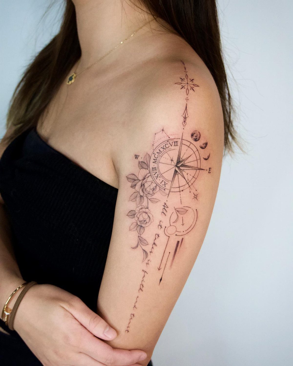 Compass and rose tattoo with geometric lines on a woman's upper arm.