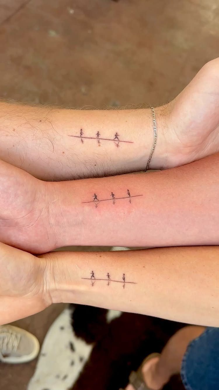 Three matching wrist tattoos of three small stick figures on a line.