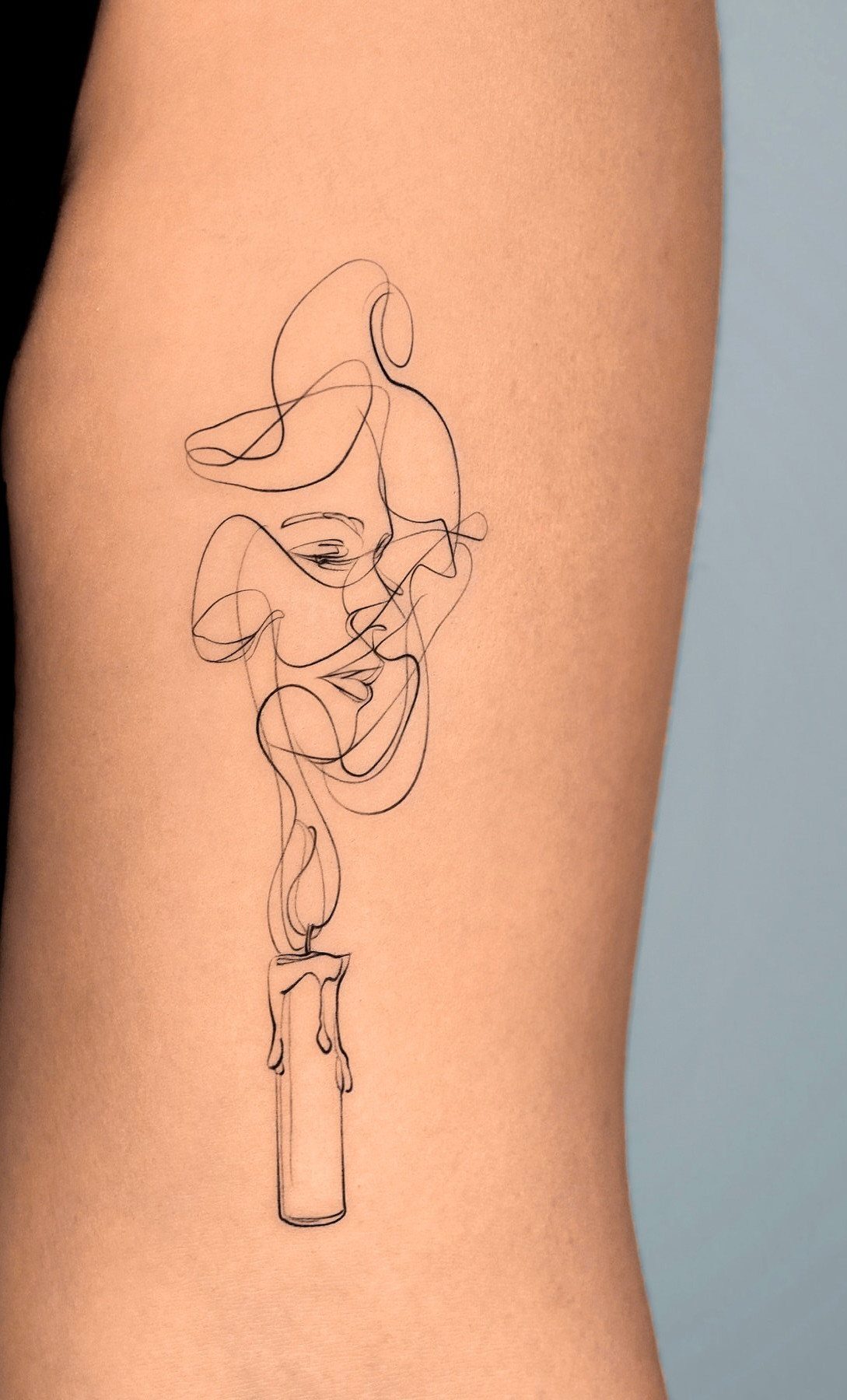 Minimalist Fine Line Tattoo Ideas: 9 Styles to Consider 4 Continuous line art tattoo of a candle with smoke forming a face profile.