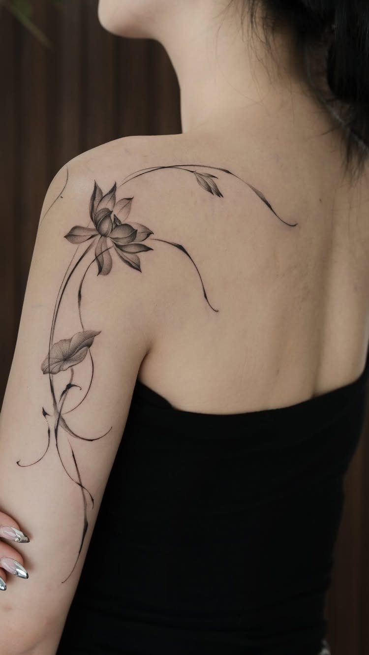 Minimalist Fine Line Tattoo Ideas: 9 Styles to Consider 2 Lotus flower tattoo with elegant flowing lines on a person's shoulder and arm.