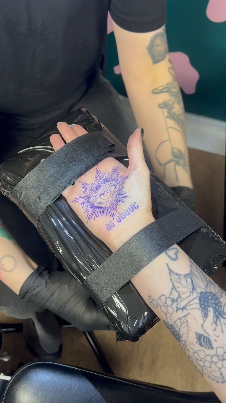 Hand with purple eye palm tattoo strapped to a black support block