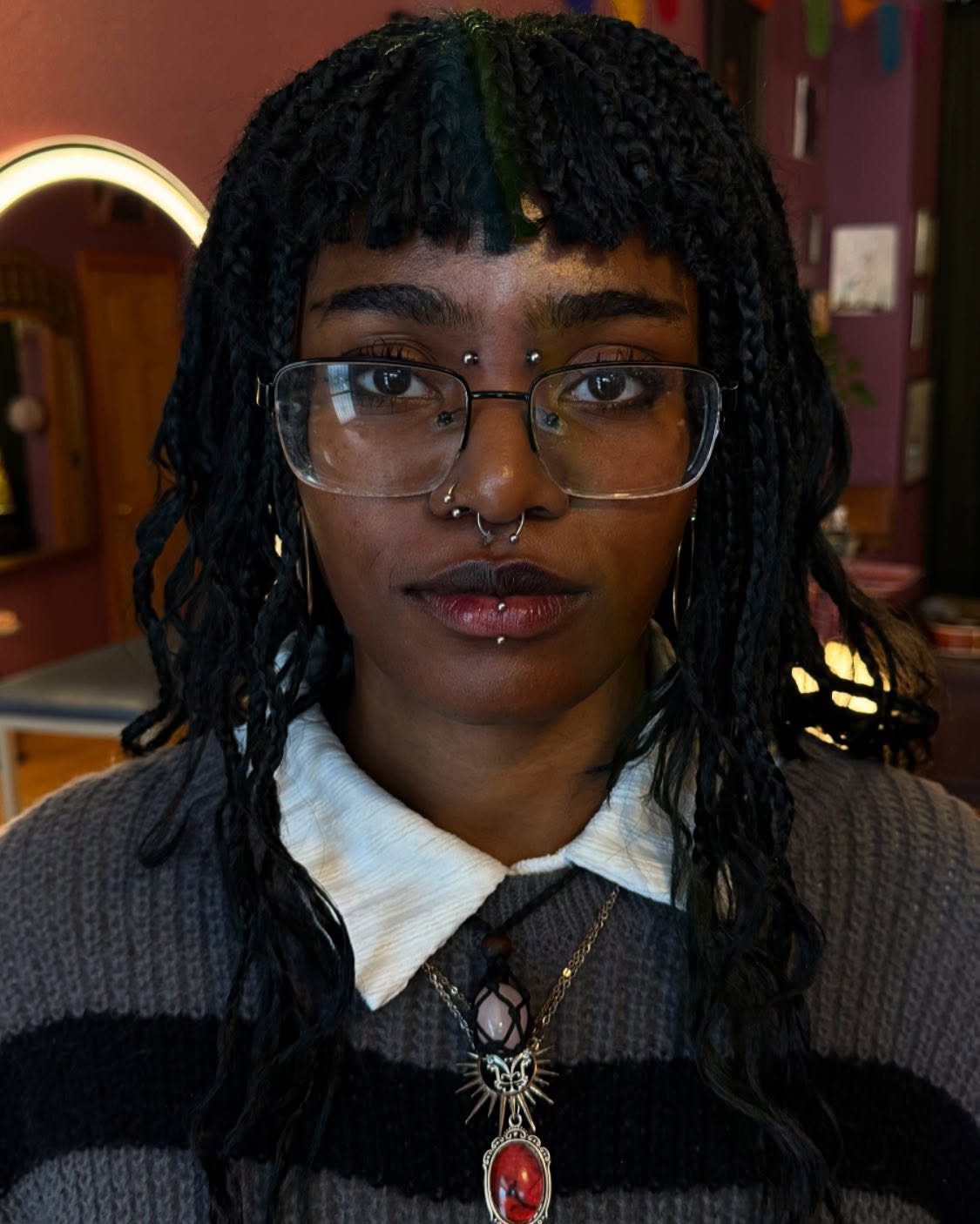 Piercing Between Eyebrows: 8 Styles and Placements 3 Person with dreadlocks and glasses featuring a bridge piercing between the eyebrows.