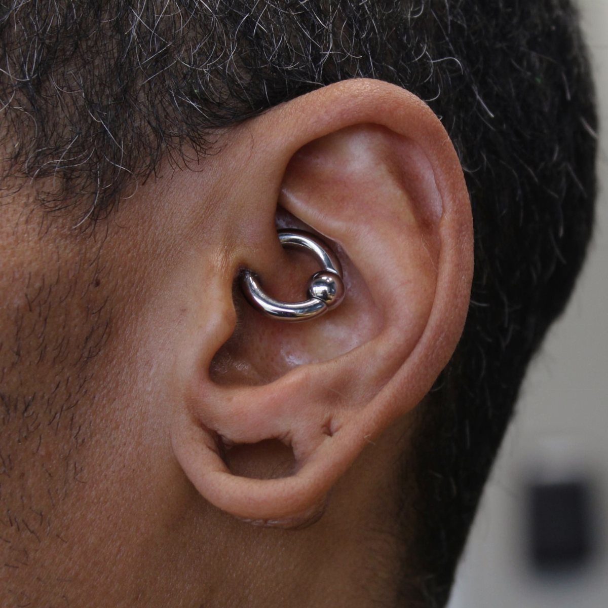 Daith piercing with a silver captive bead ring in the inner ear cartilage.