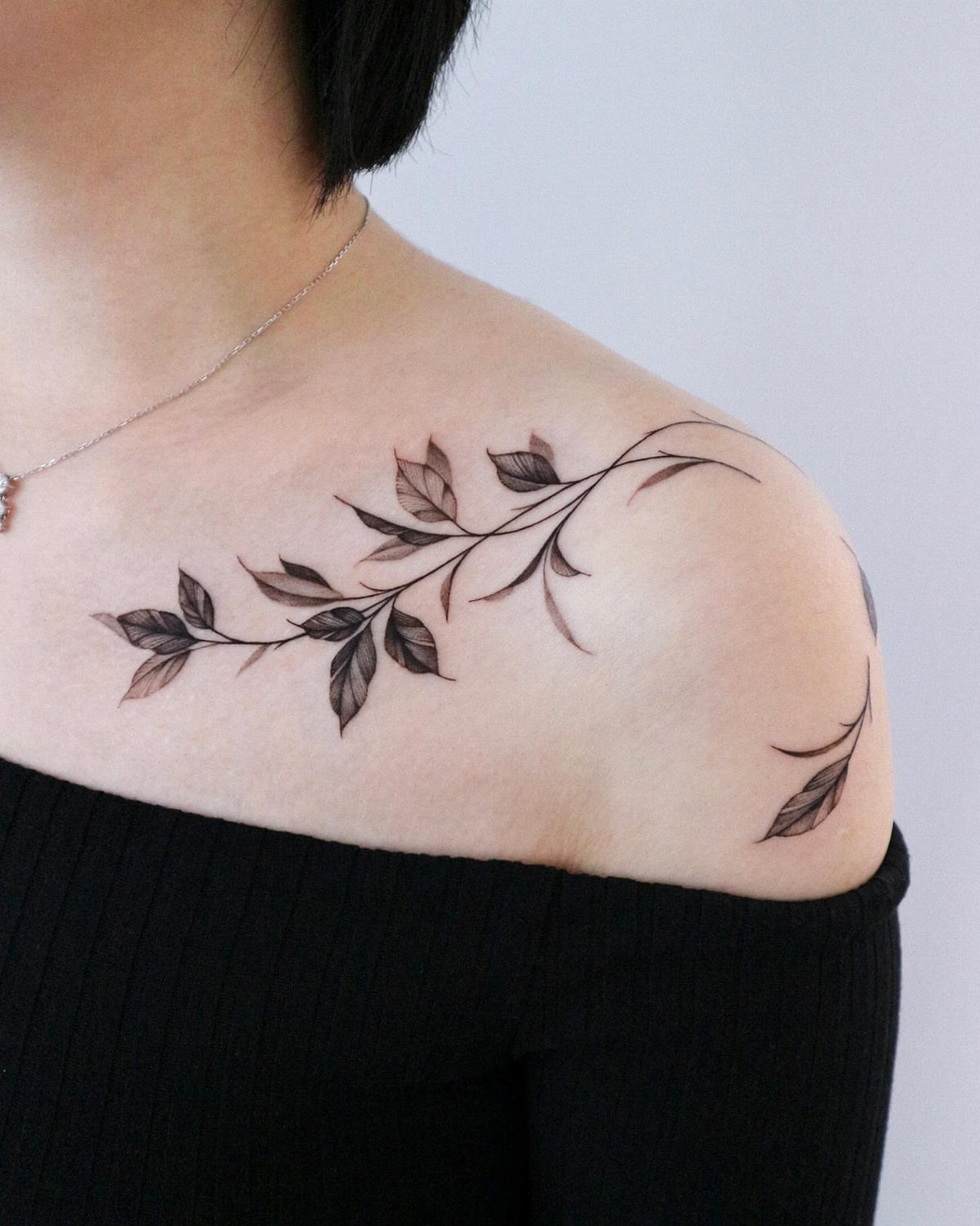 Leafy branch tattoo on a woman's collarbone and shoulder area