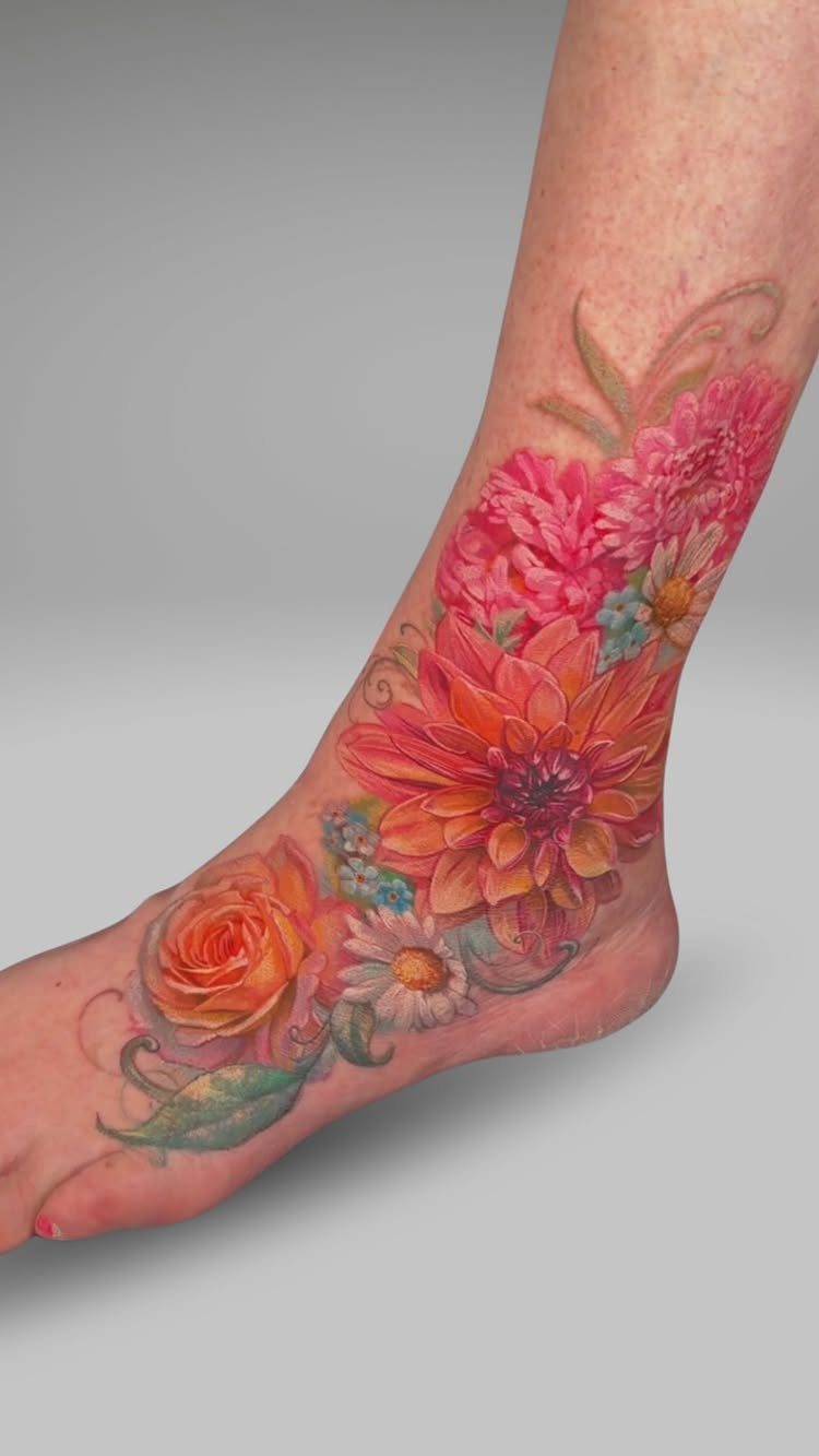 Colorful floral tattoo covering the top of a foot and lower ankle