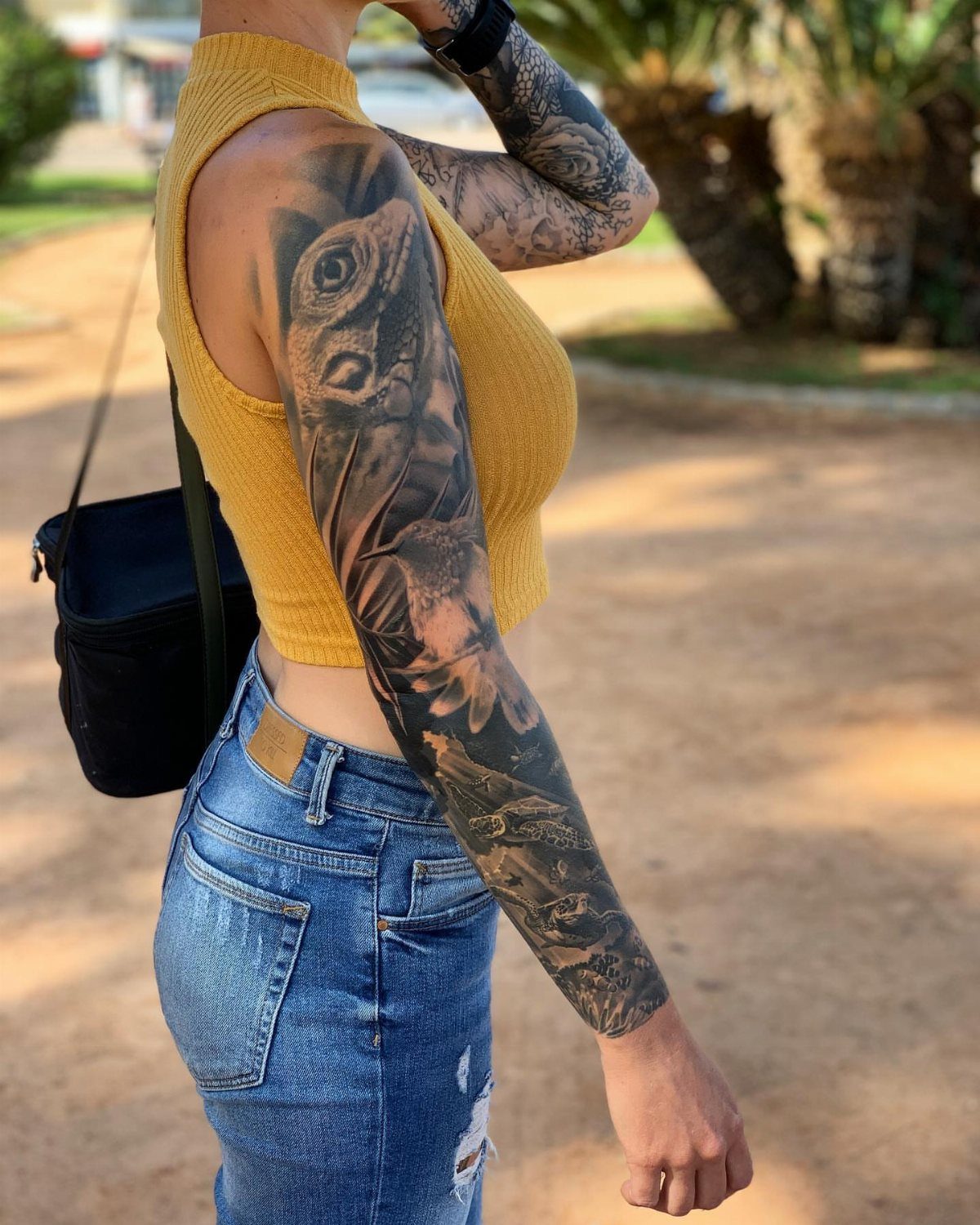 Woman with a large lizard tattoo covering her upper arm and forearm