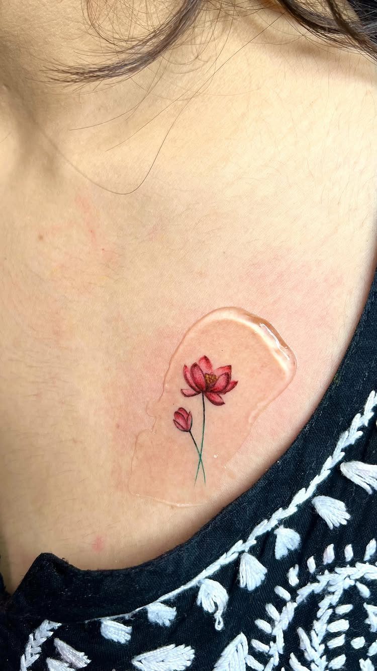 Pink lotus flower tattoo on a collarbone covered by a clear bandage.