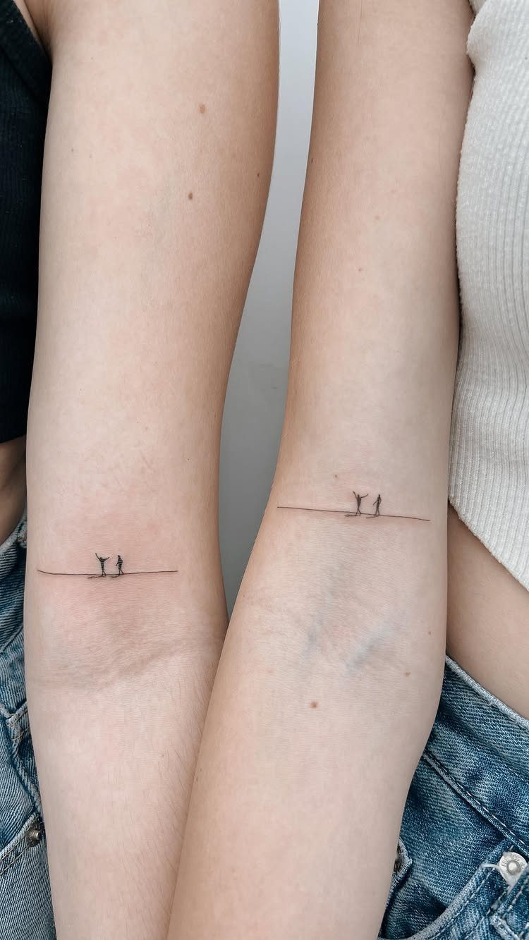 Two matching minimalist tattoos of tiny figures on a line on two forearms.