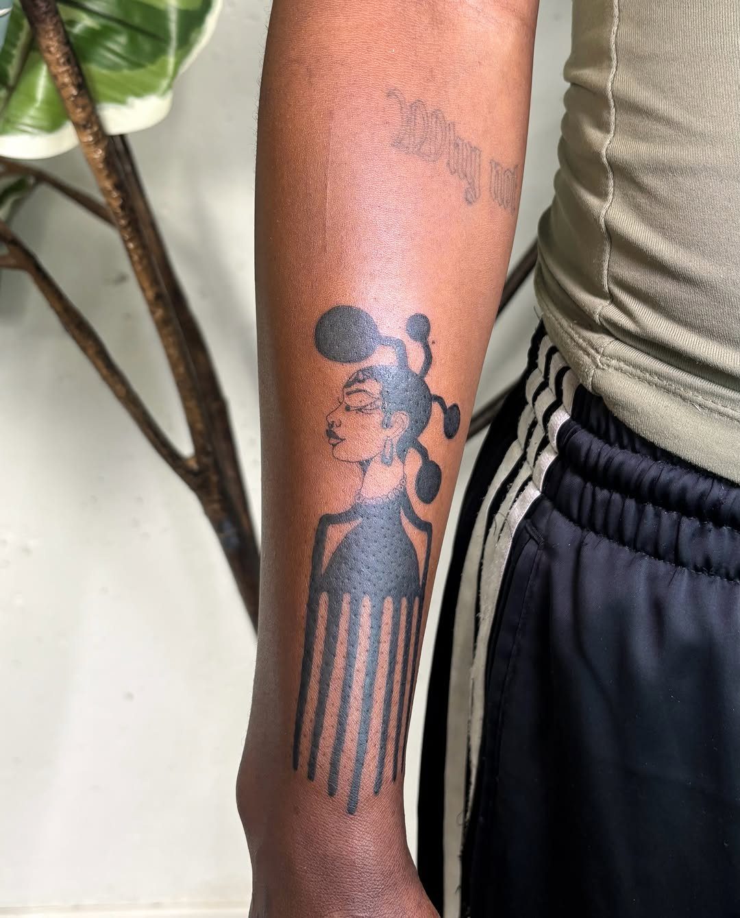 8 Pro Black Tattoos Ideas for Bold, Meaningful Ink 8 Black ink tattoo of a woman's profile with an afro on a forearm.