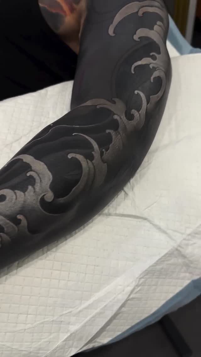 8 Pro Black Tattoos Ideas for Bold, Meaningful Ink 6 Tattoo sleeve with solid black ink and grey organic wave patterns on an arm.
