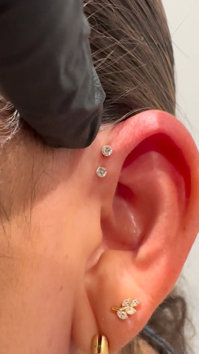 Ear with two diamond studs in the forward helix and a gold leaf lobe piercing.