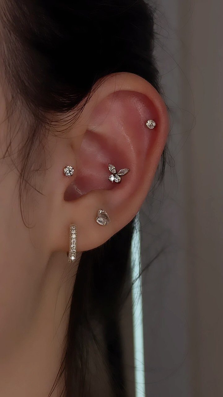Ear with multiple diamond stud piercings, including a small stud on the tragus.