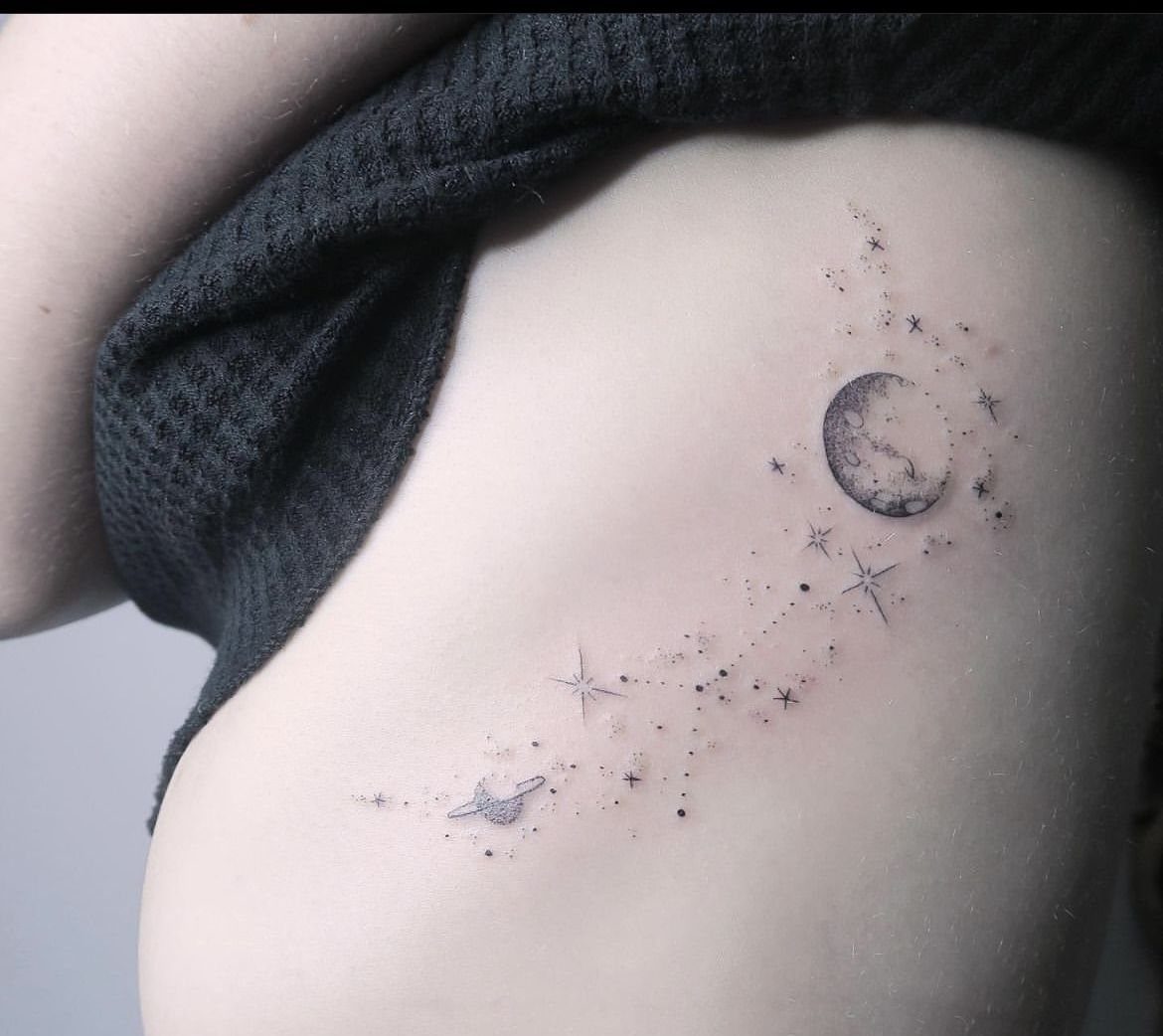 Rib Tattoos for Women: 9 Floral, Celestial and Script Ideas 9 Ribcage tattoo featuring a detailed full moon, small stars, and a ringed planet.
