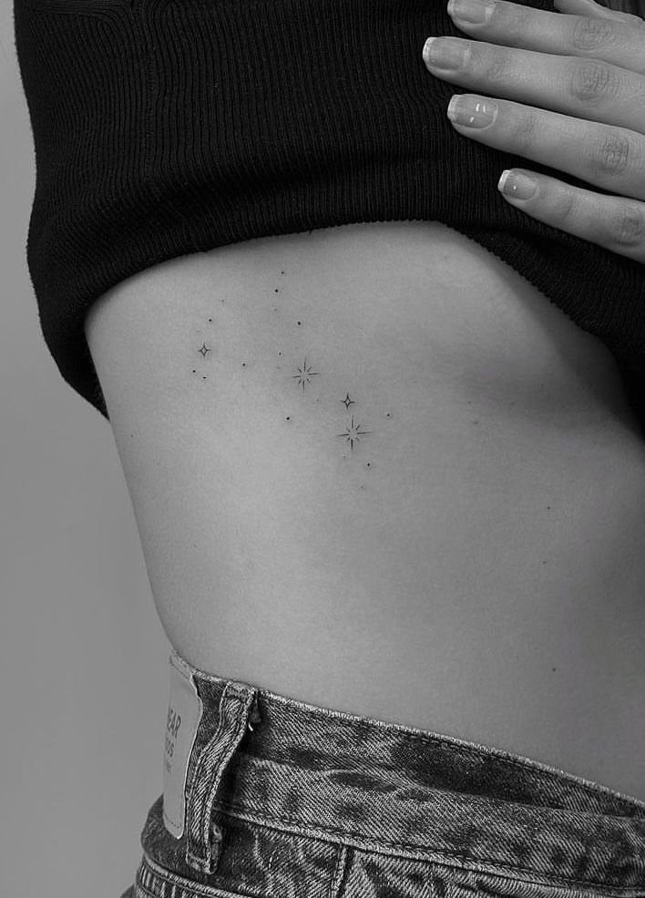 Rib Tattoos for Women: 9 Floral, Celestial and Script Ideas 6 Small star tattoos on the ribcage of a person in denim jeans.