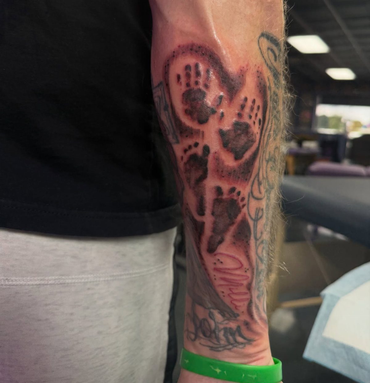 Baby footprint tattoos inside a red heart on a person's forearm.