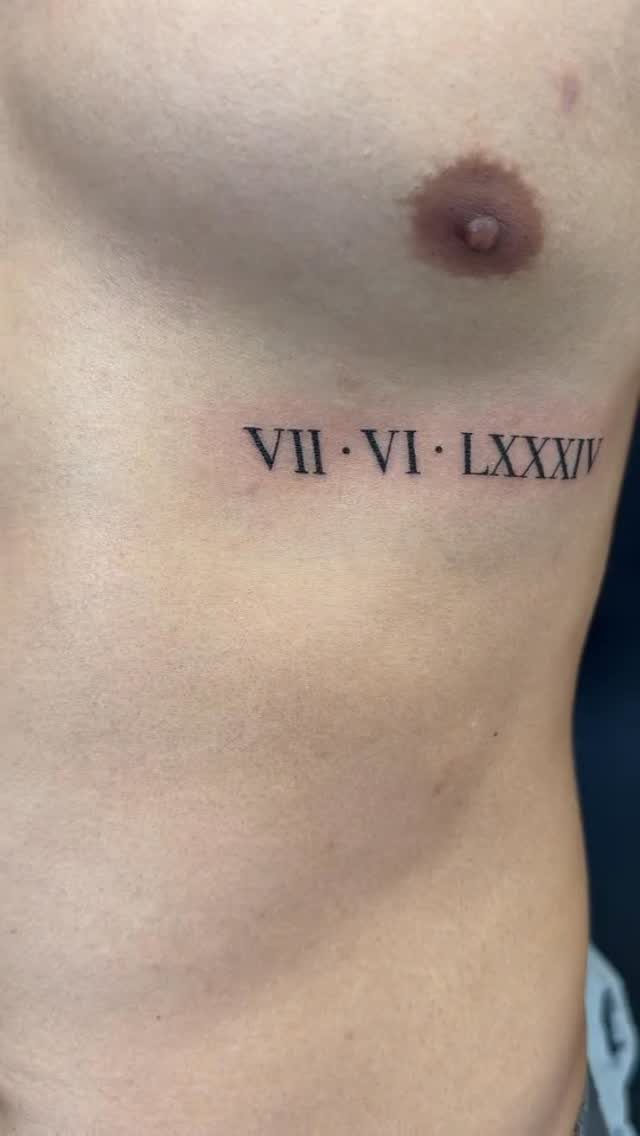 Roman numeral date tattoo on the side of a person's ribcage.