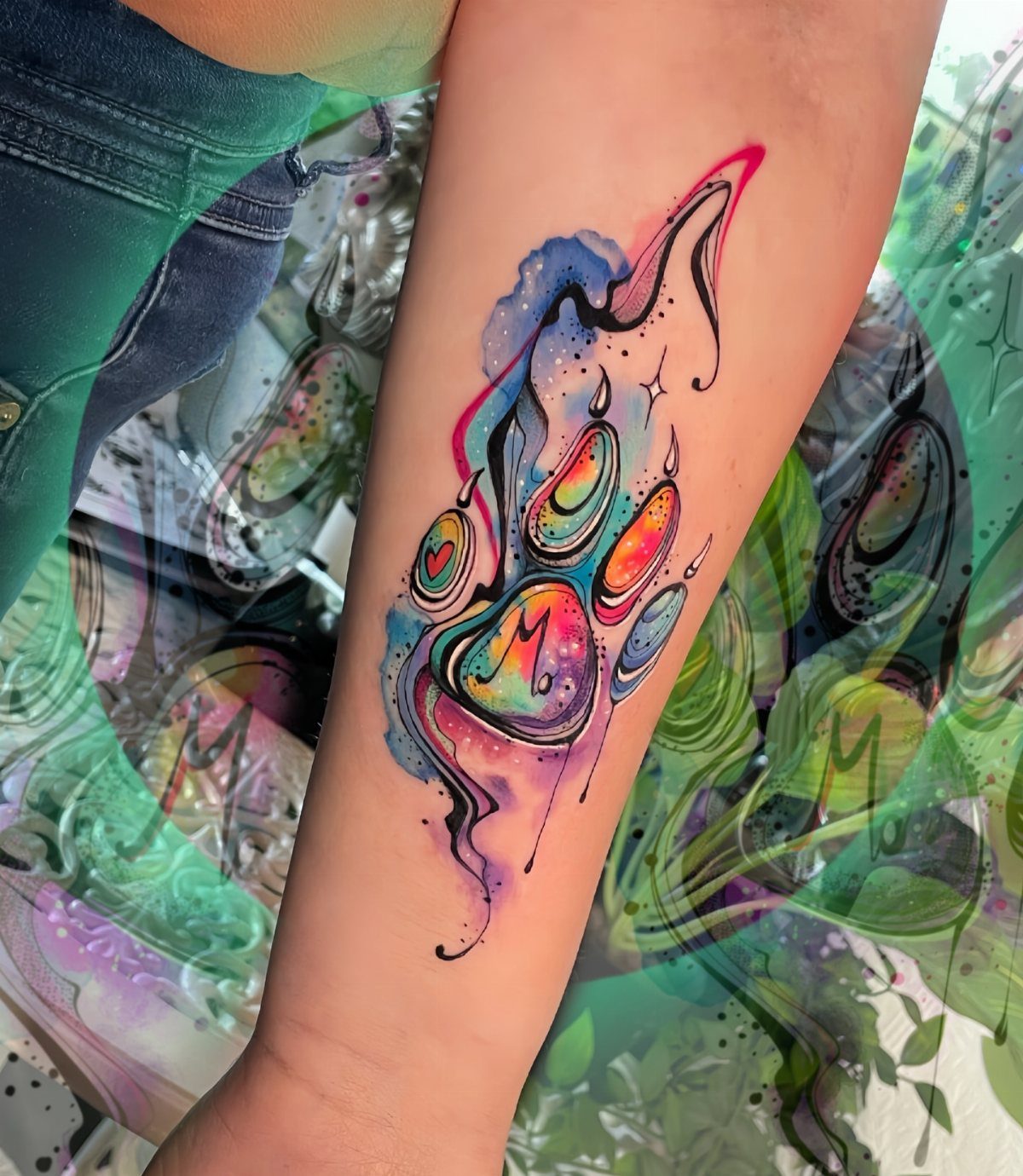 Watercolor paw print tattoo with vibrant colors on a person's forearm.