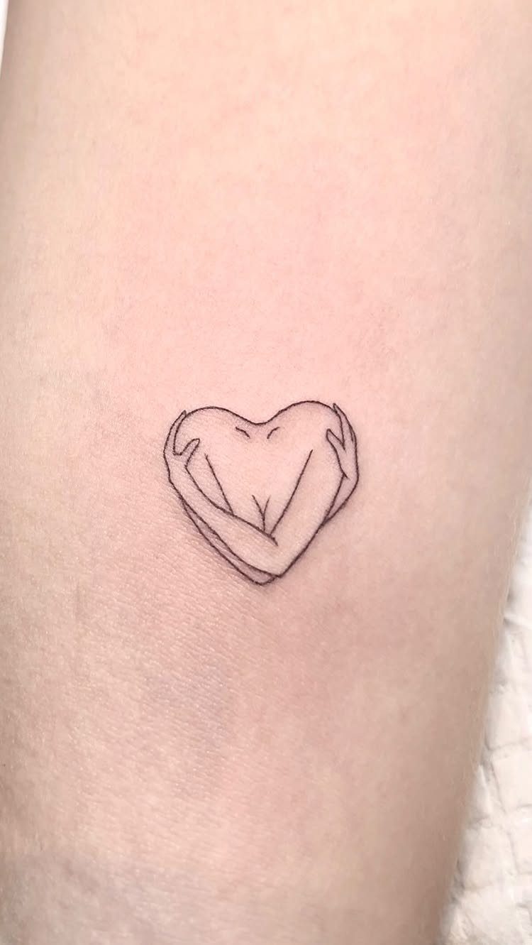 26 Self Tattoo Ideas for Simple, Meaningful Ink 10 Small black ink tattoo of arms hugging a heart on fair skin