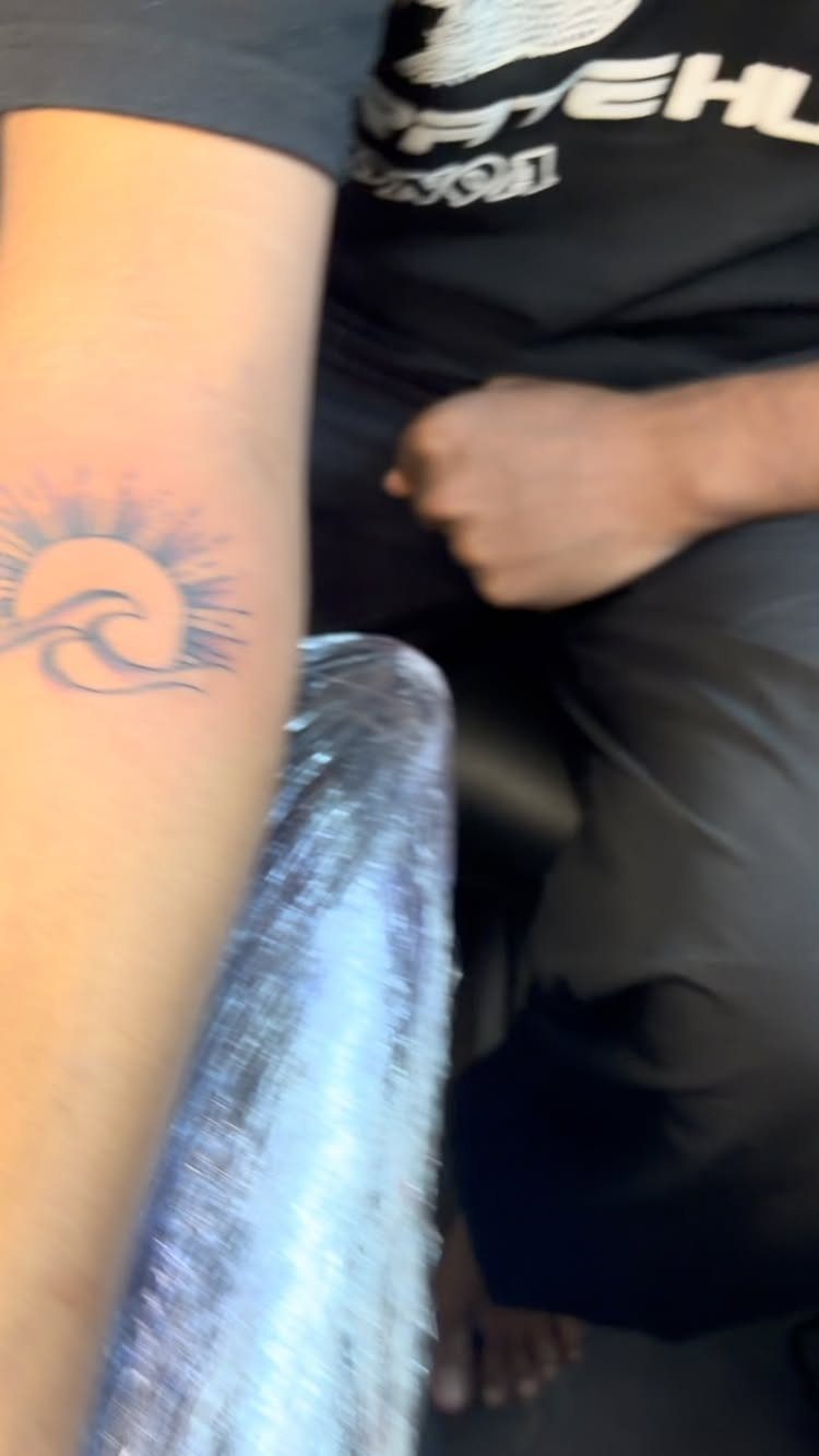 26 Self Tattoo Ideas for Simple, Meaningful Ink 5 Sunrise and wave tattoo on a person's forearm in black ink.