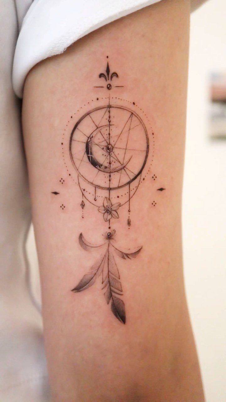 9 Side Arm Tattoos for Animals, Script, Florals and More 4 Dreamcatcher tattoo with moon and feathers on a person's upper arm.