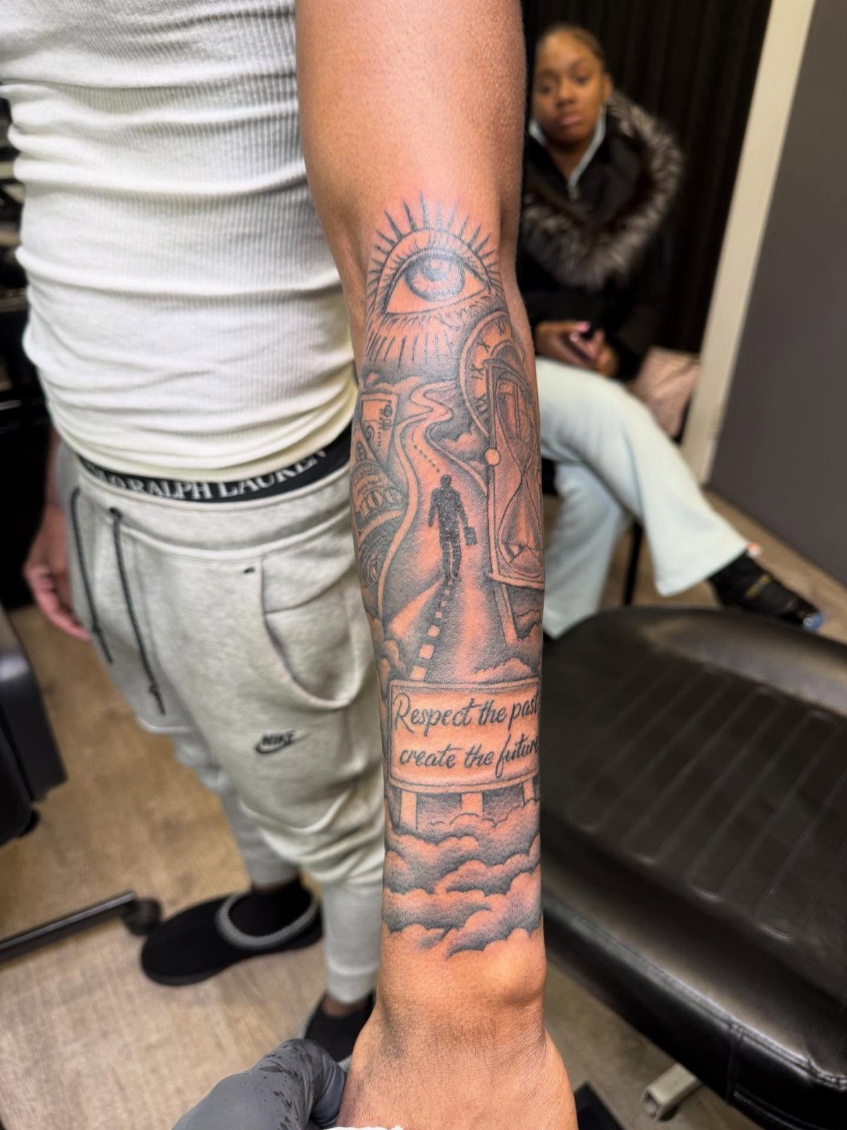9 Side Arm Tattoos for Animals, Script, Florals and More 1 Detailed black and grey forearm tattoo featuring an eye, a path, and script text.