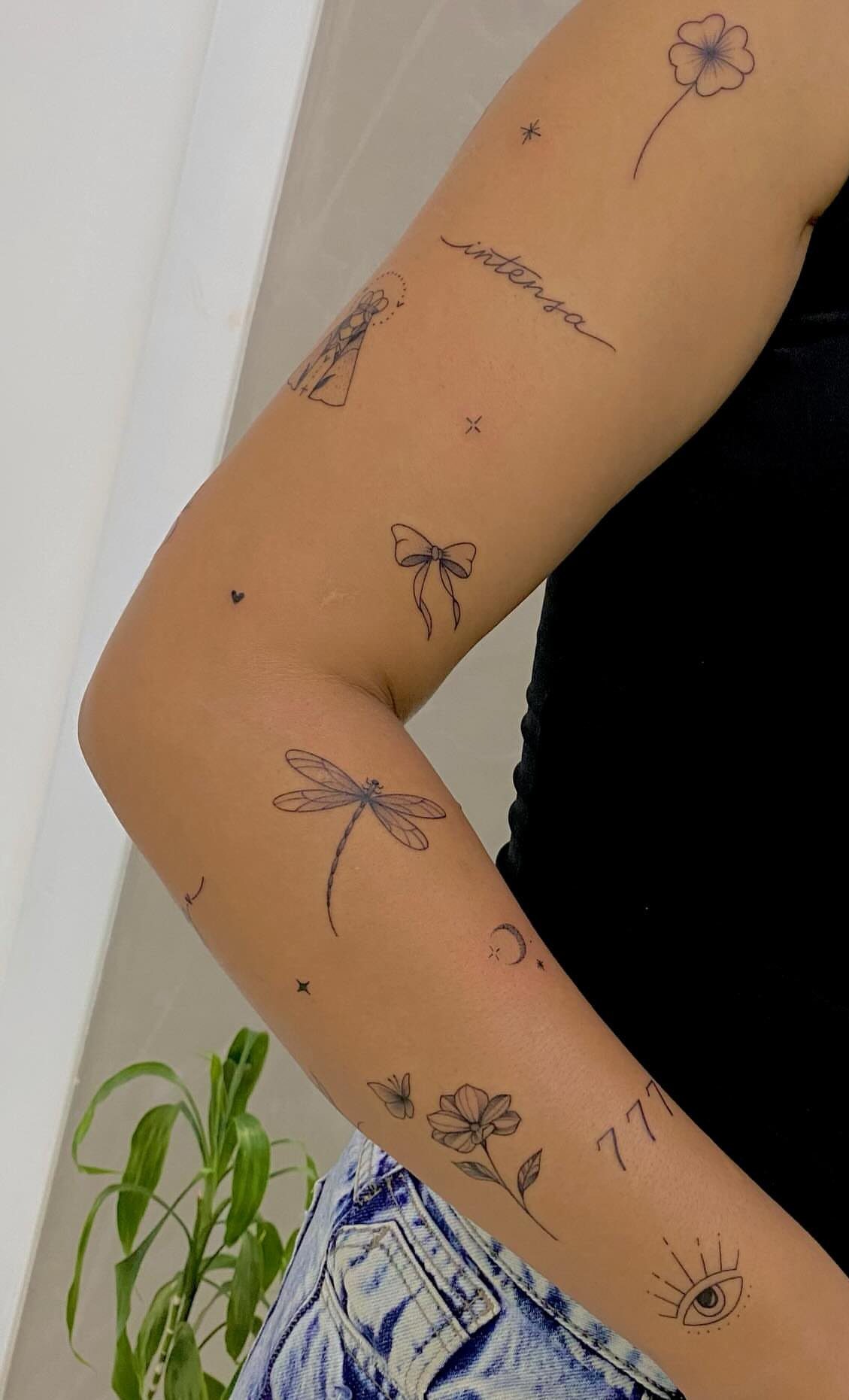 9 Side Arm Tattoos for Animals, Script, Florals and More 9 Arm with various small black ink tattoos including a dragonfly and floral designs.