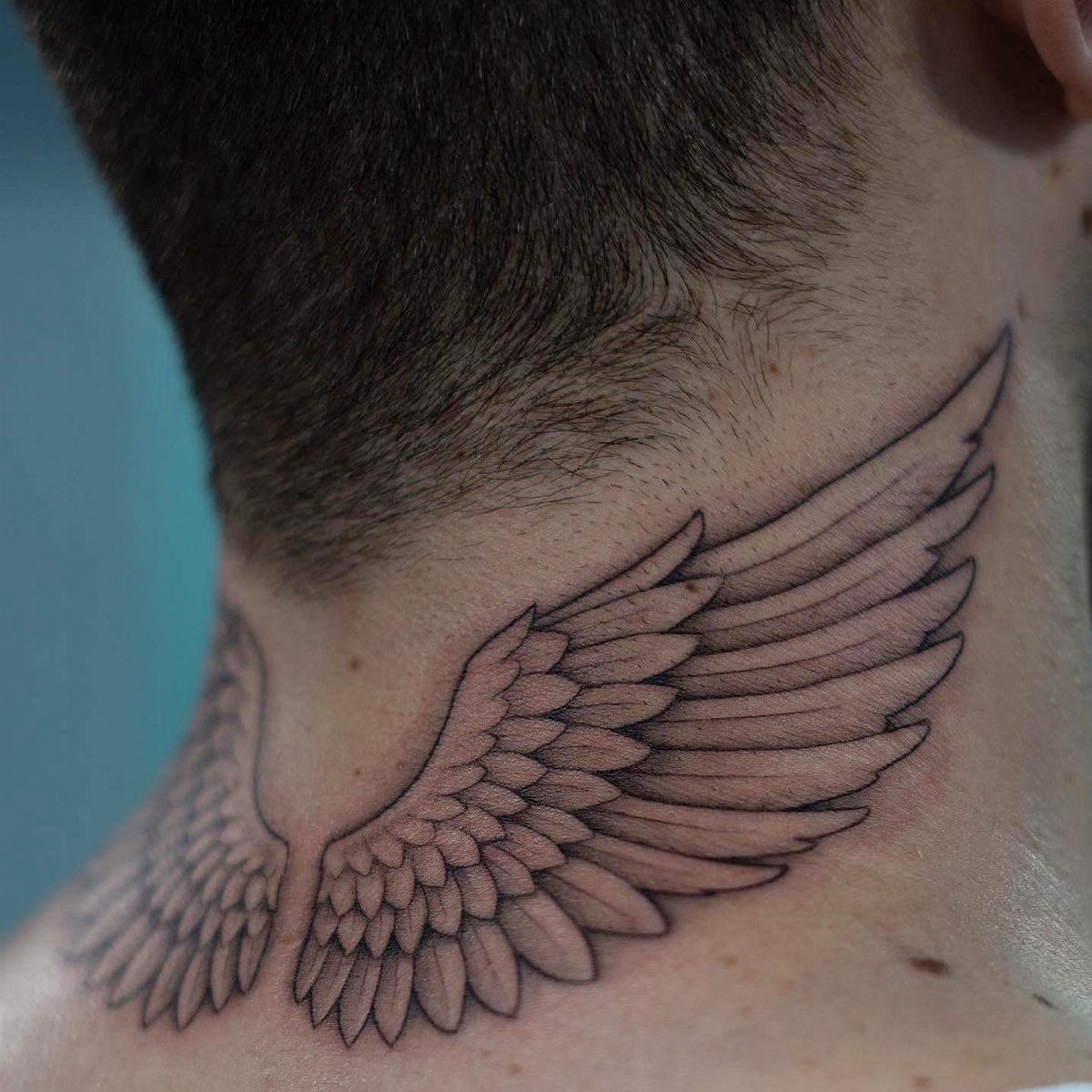 21 Side Neck Tattoo Ideas for Bold, Meaningful Designs 5 Angel wing tattoo on the back and side of a person's neck.