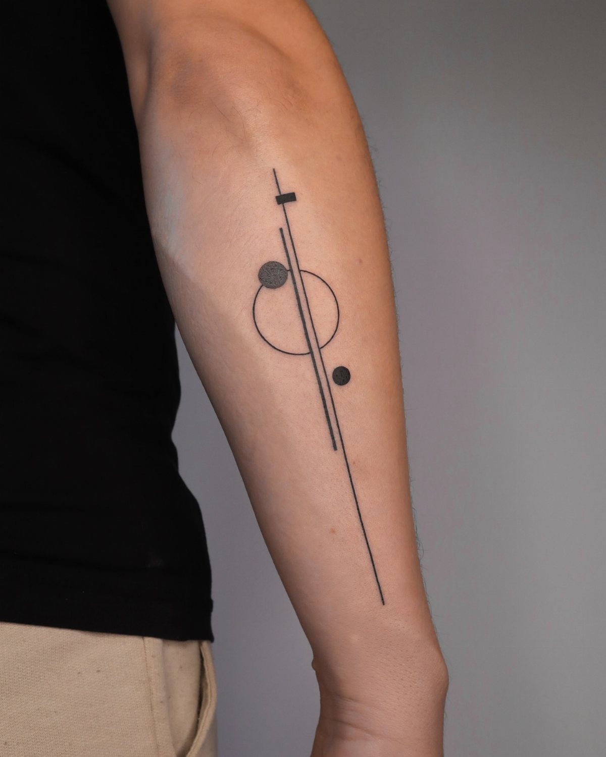 Geometric tattoo with a line and circle on a person's inner bicep.
