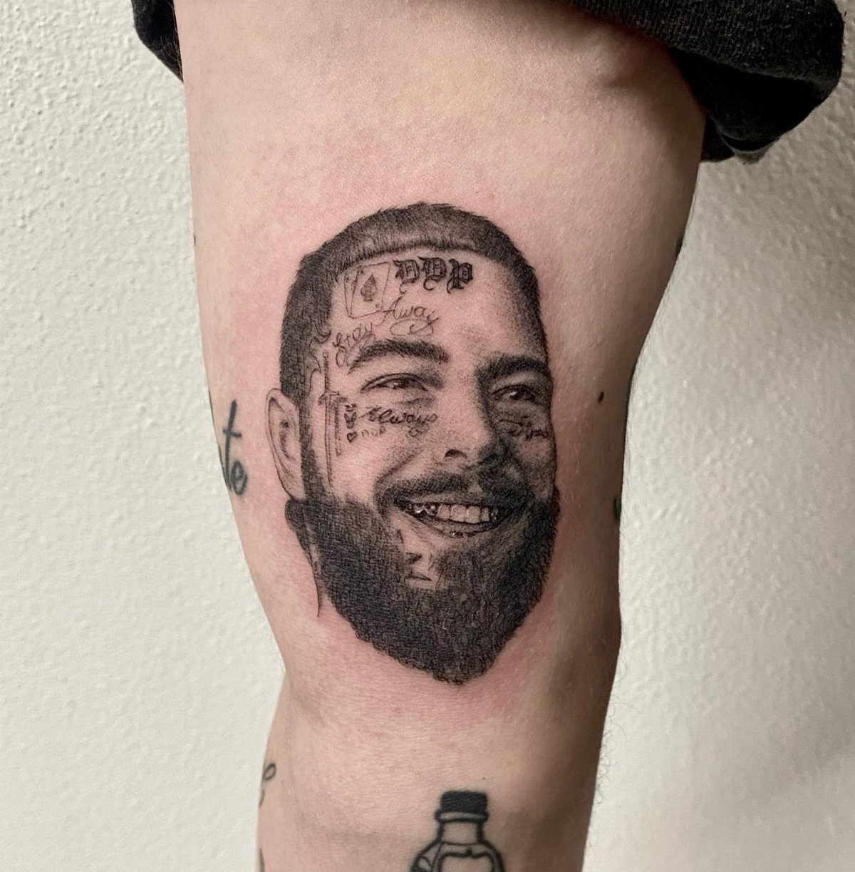Realism tattoo of a bearded man's face on a person's inner bicep.
