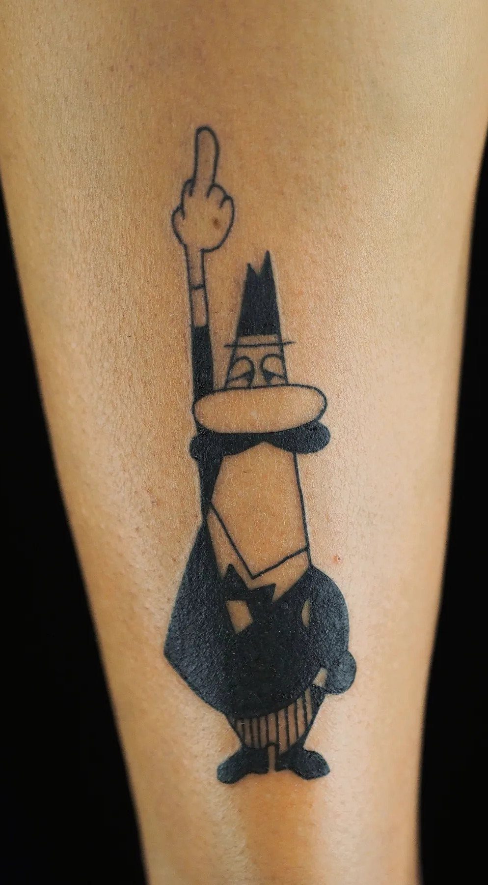 Cartoon character tattoo in black ink on a person's bicep area.